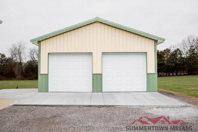 24x30x10 garage with cream siding, light green accents, and two white garage doors