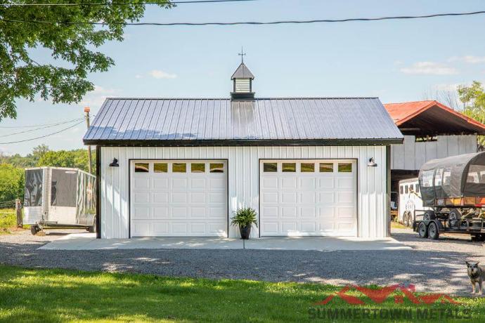 30x30x10 farm-style garage with white siding, dark accents, black roof, two white garage doors, and matching cupola