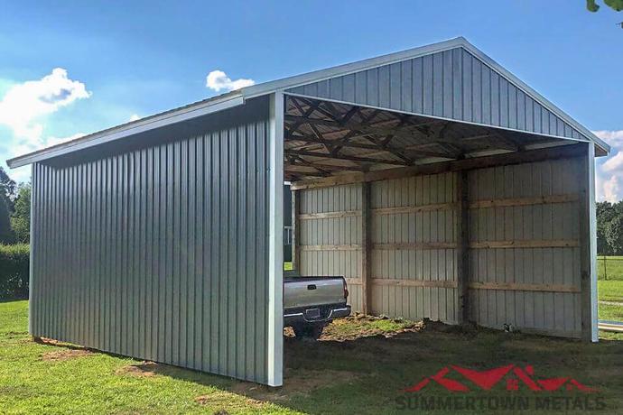 Hay barn with gray siding, white accents, and a truck parked underneath