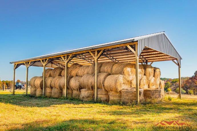 Large open hay barn with gray paneling on top and hay bales stored underneath