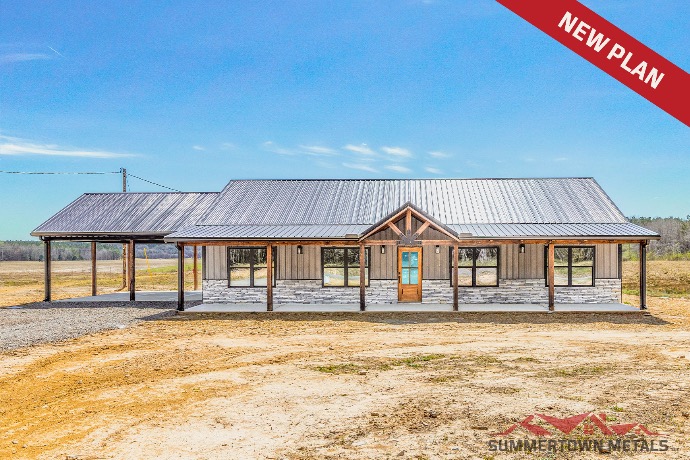 Long East Fort Deluxe barndominium with gray siding, gray stones, wood accents, dark roof, large front porch, and carport