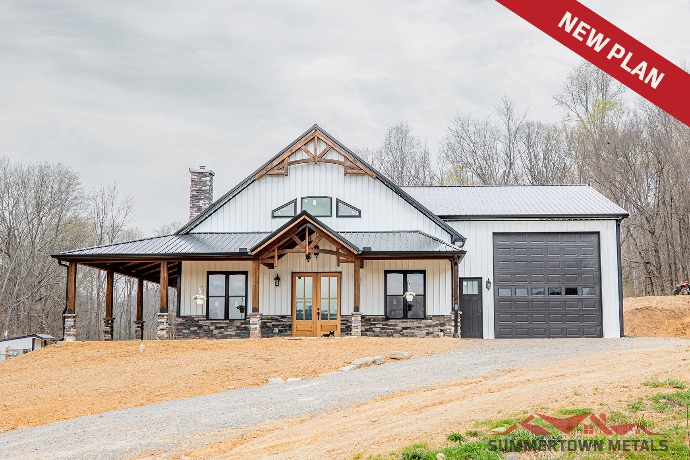 Two-story Ridge Crest barndominium with white siding, black roof, wood and stone exterior accents, and black garage door